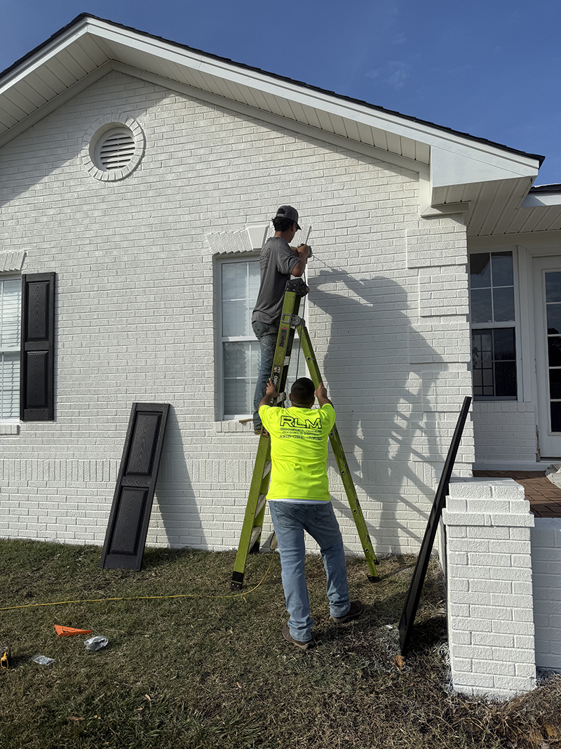 Team members painting the exterior trim of a home.