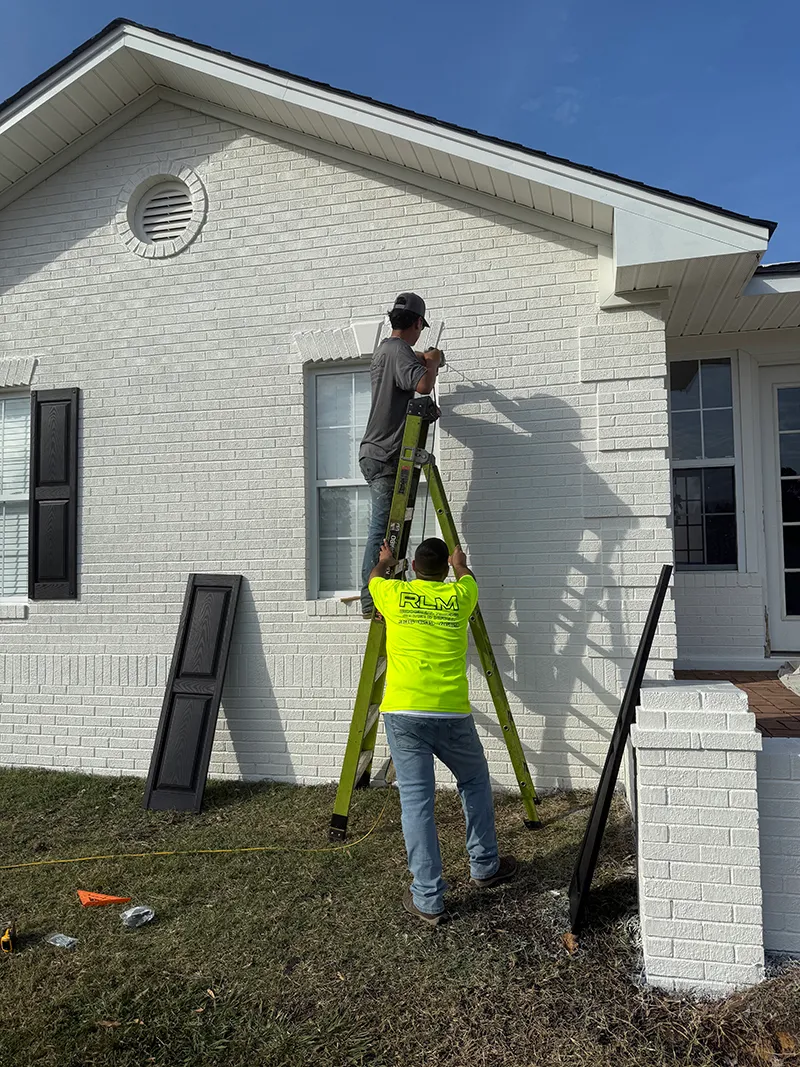 Team members painting the exterior trim of a home.
